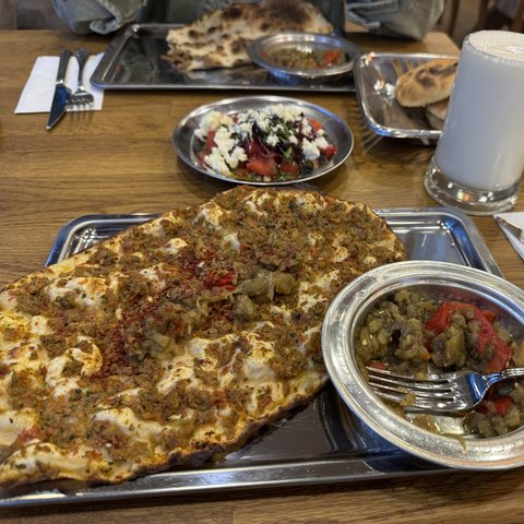 Metal tepside bütün bir Antep lahmacunu, yanında patlıcan söğürme